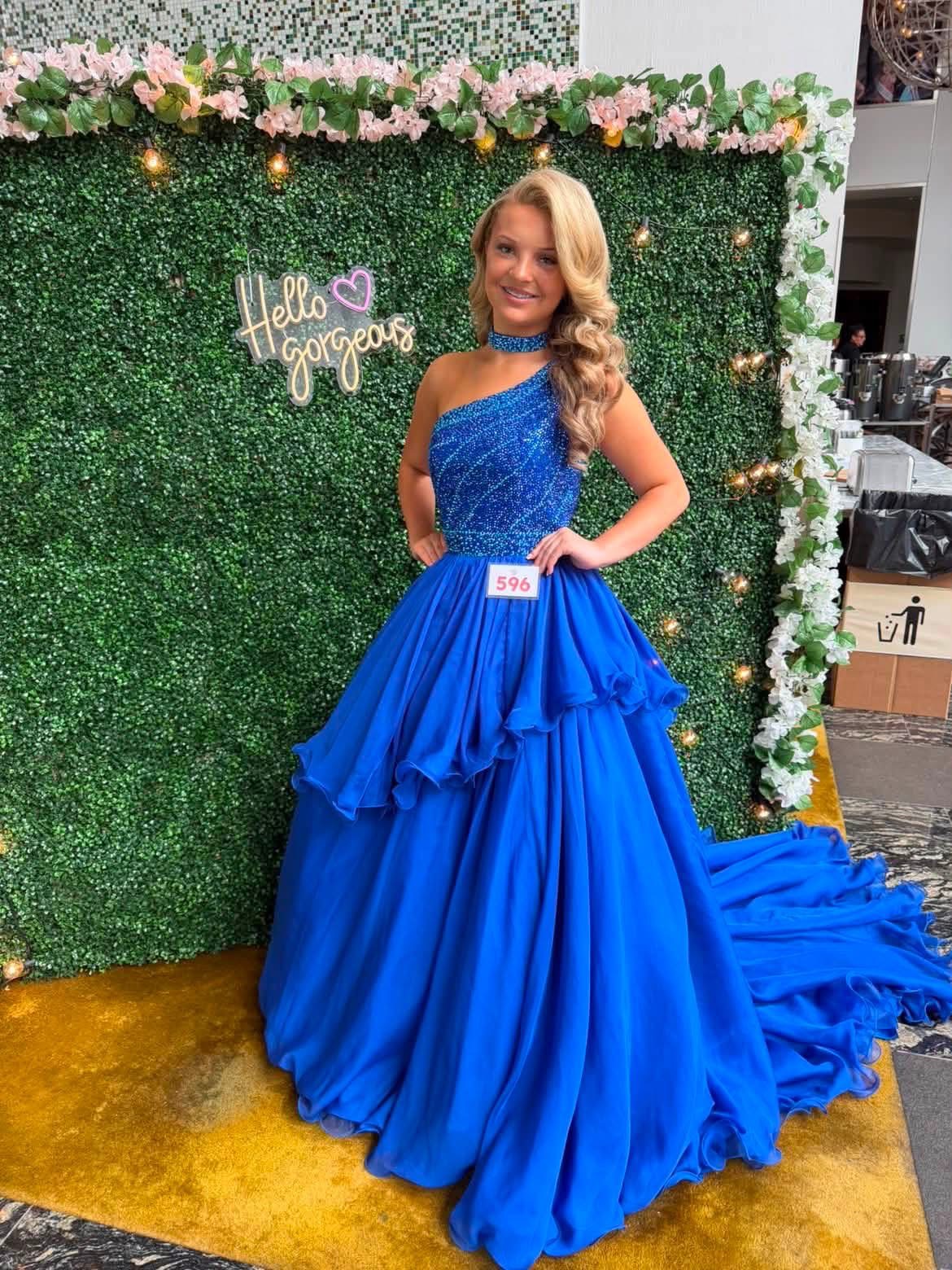Contestant in a blue evening gown against a garden backdrop