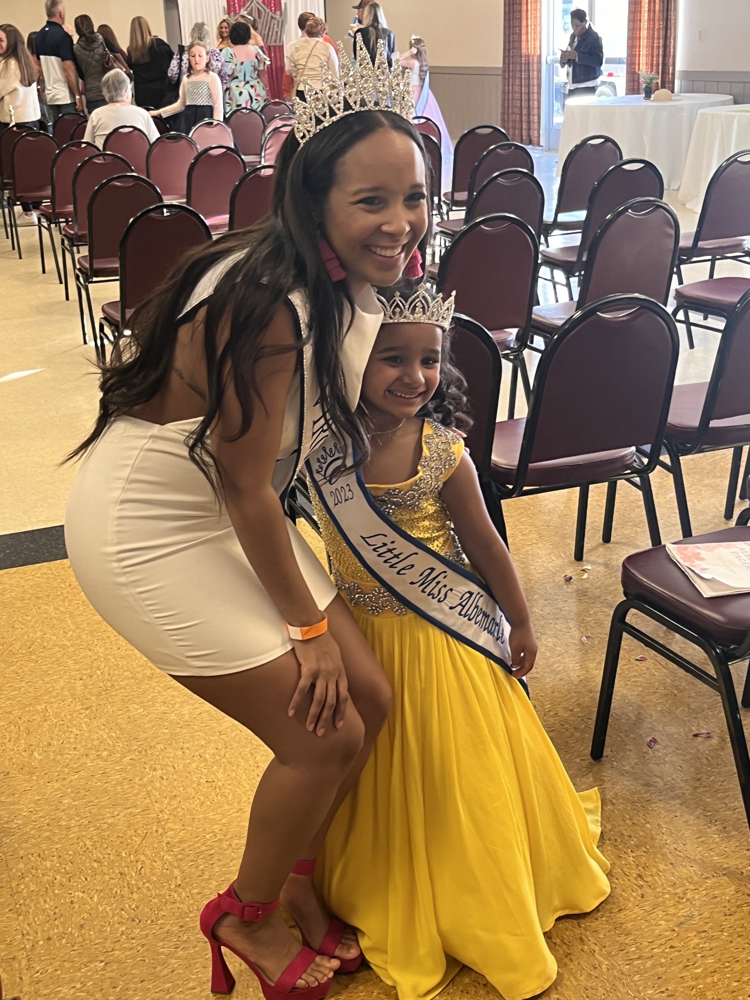 Pageant coach celebrating with a contestant in a yellow evening gown